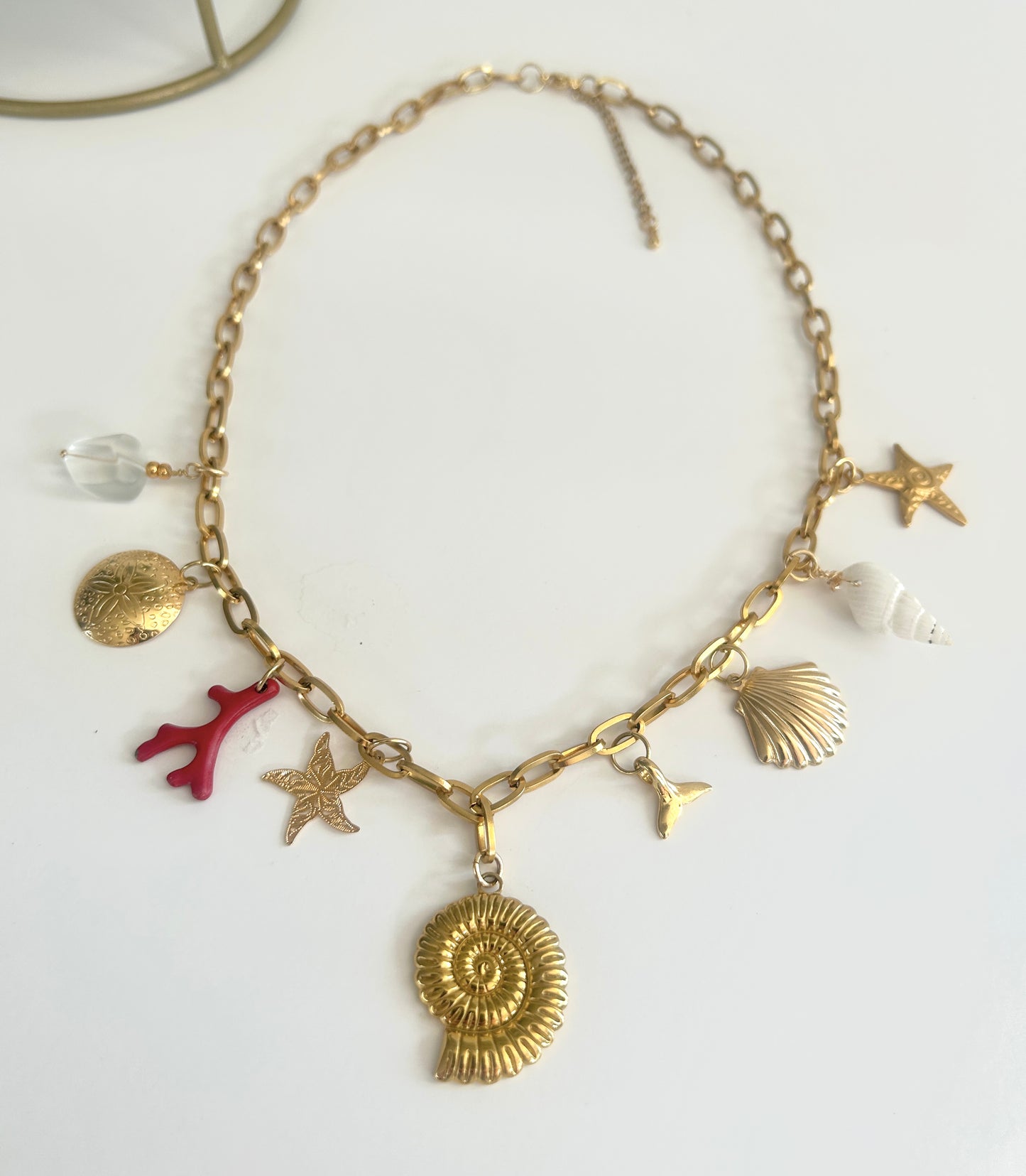 Gold necklace with various charms on a white background