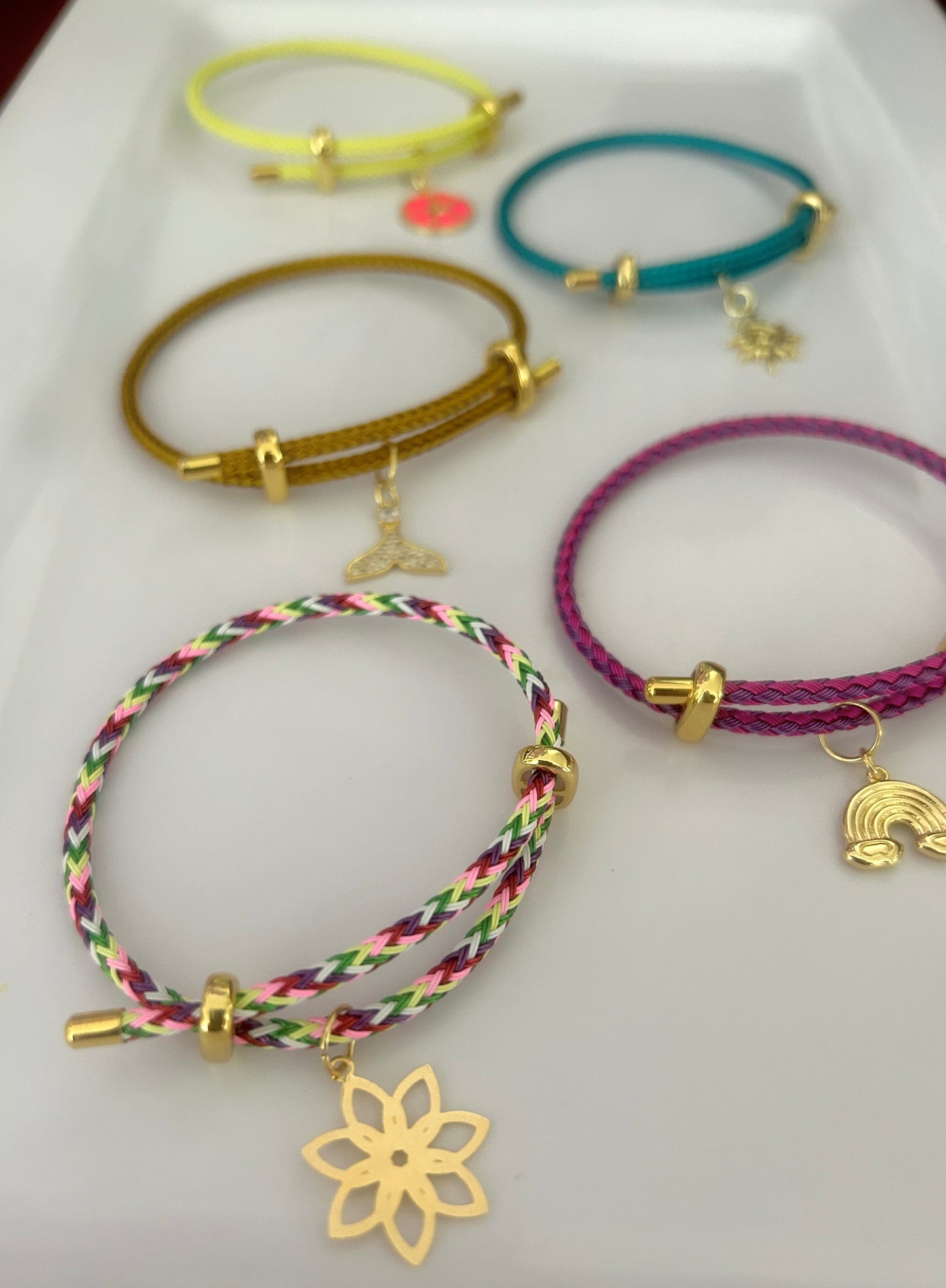 Collection of colorful bracelets with charms on a white background