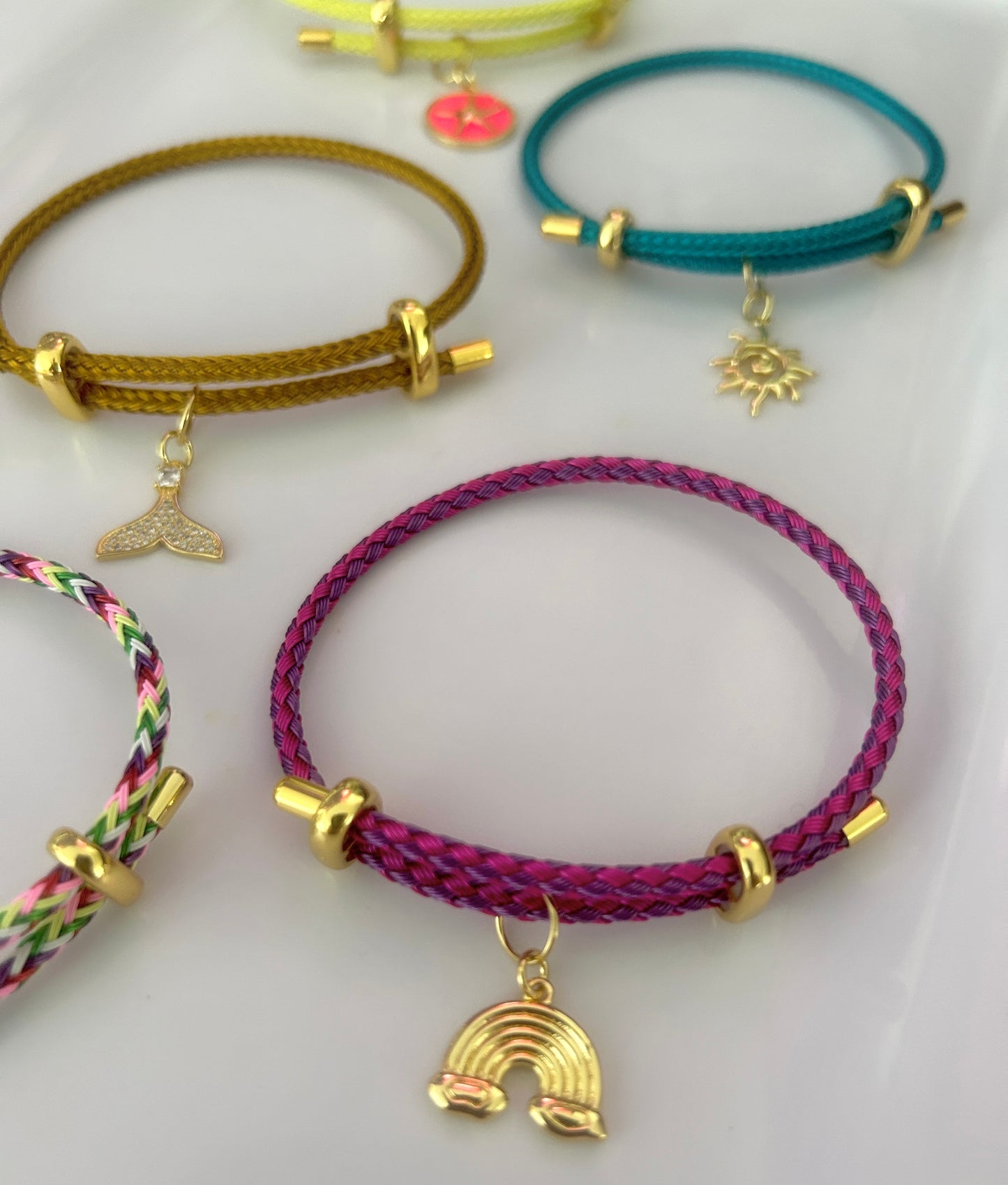 Collection of colorful bracelets with charms on a white background