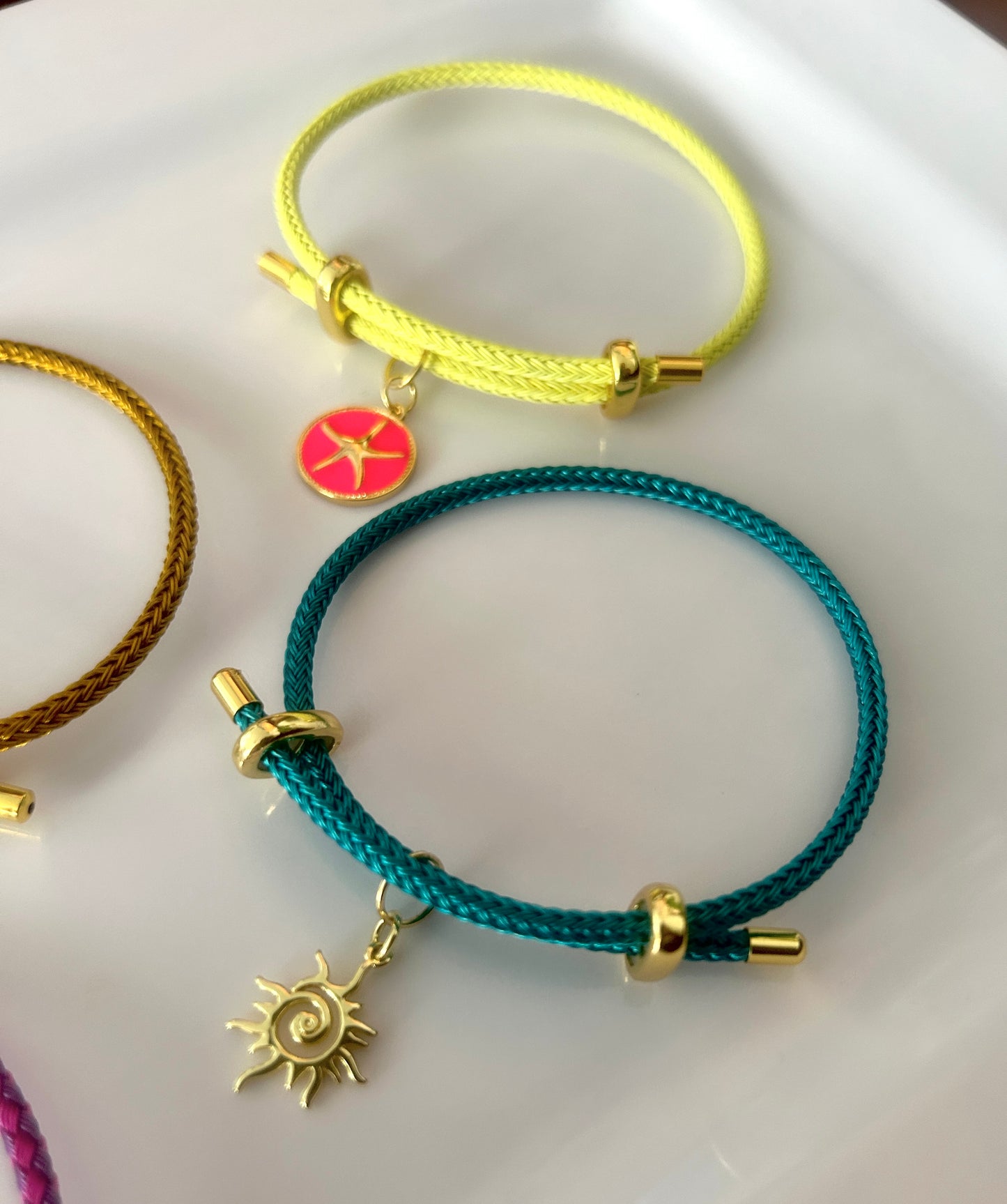 Three colorful bracelets with charms on a white surface