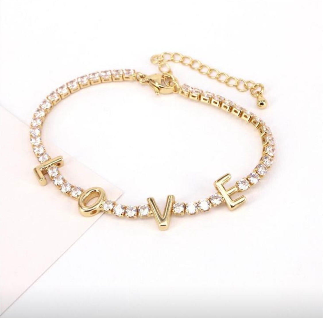 Gold bracelet with 'LOVE' charm on a white background