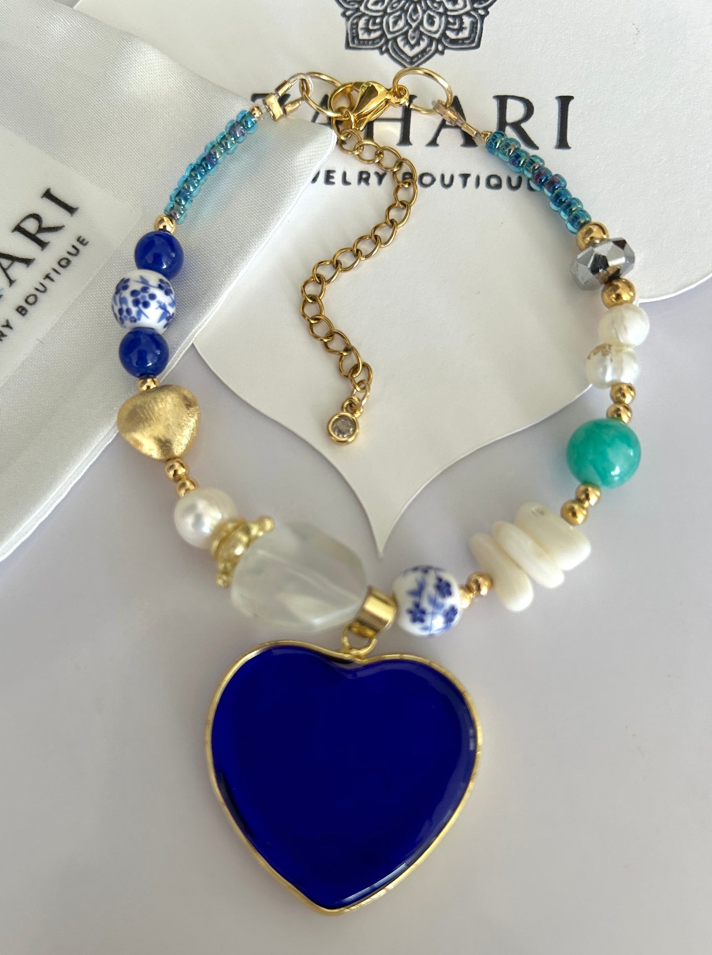Necklace with blue heart pendant and beaded chain on a white background