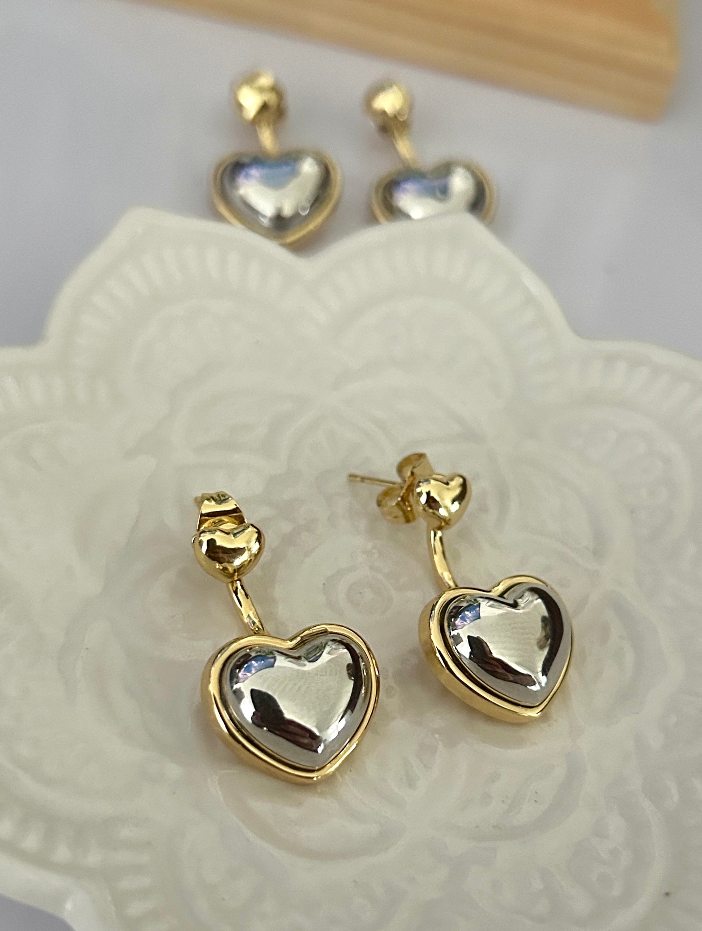 Gold heart-shaped earrings on a white lace doily