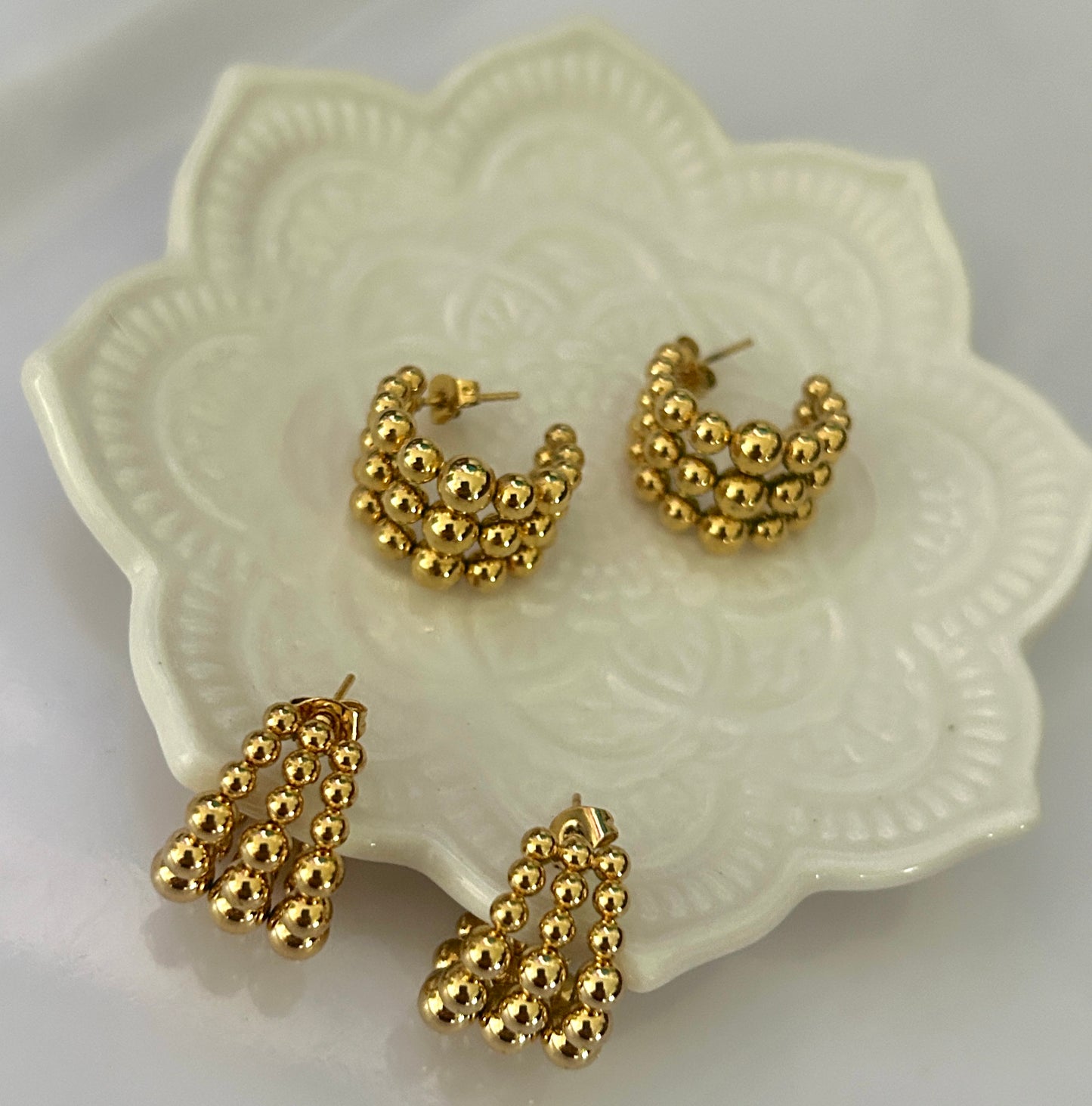 Gold hoop earrings on a decorative white dish