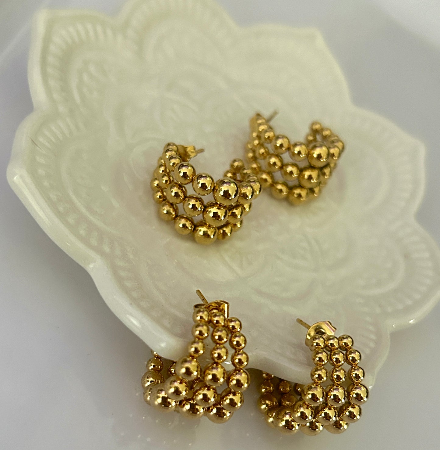 Gold hoop earrings on a decorative white dish