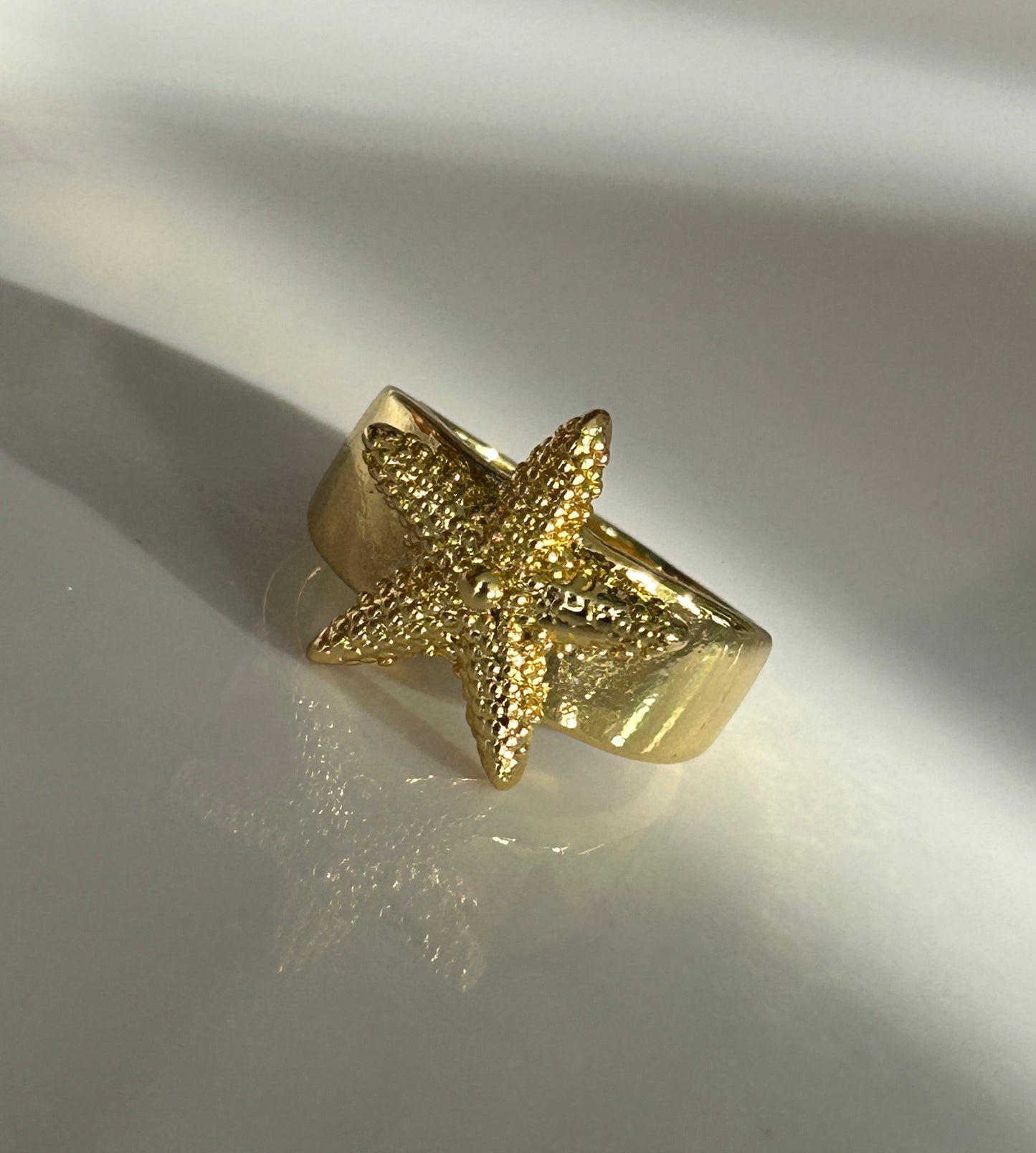 Gold starfish ring on a reflective surface