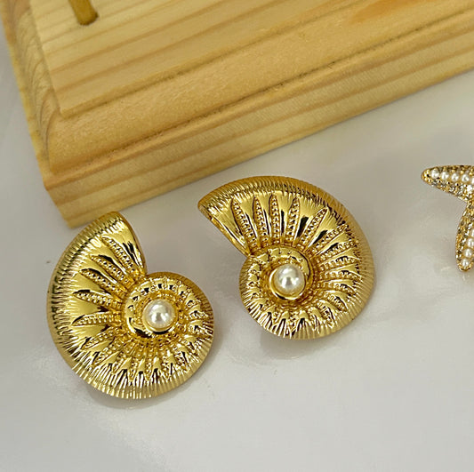 Gold earrings with pearl centers on a light background