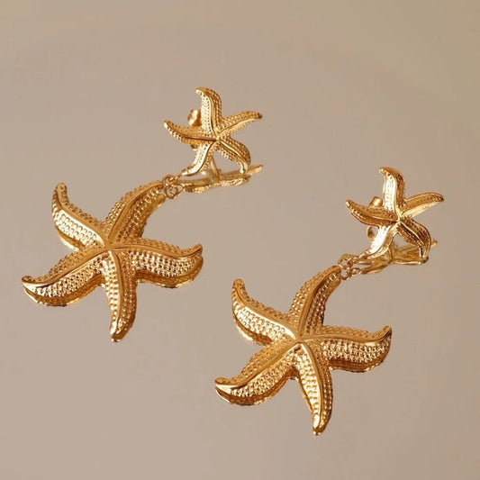Gold starfish earrings on a beige background