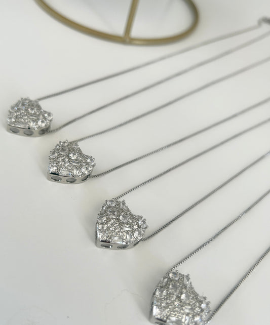 Silver necklaces with heart-shaped diamond pendants on a white background