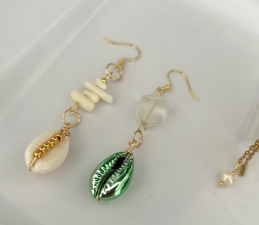 Pair of earrings with shell and green leaf design on a white background