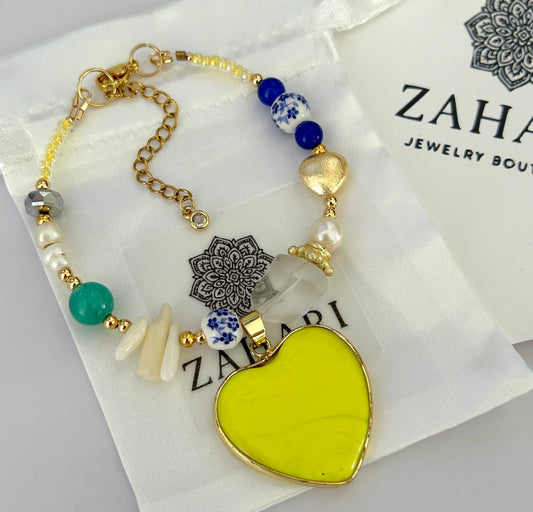 Bracelet with yellow heart pendant and blue beads on a Zaha Jewelry Boutique card.