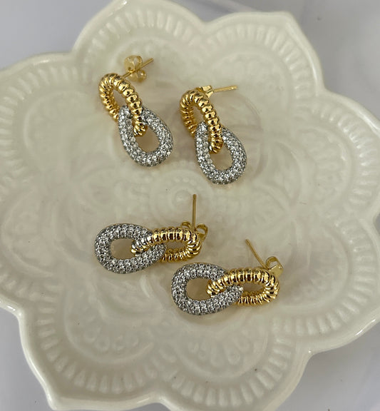 Pair of gold and silver hoop earrings on a decorative white dish.