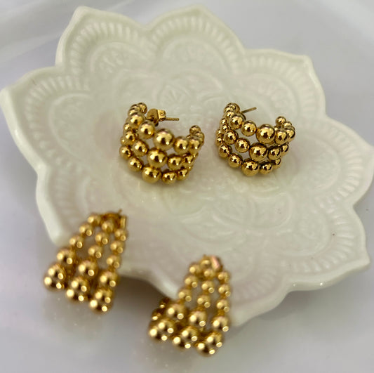 Gold hoop earrings on a decorative white dish