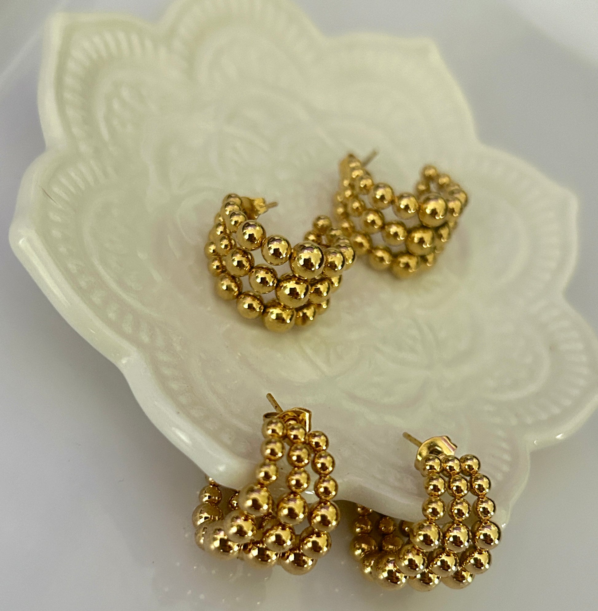 Gold hoop earrings on a decorative white dish
