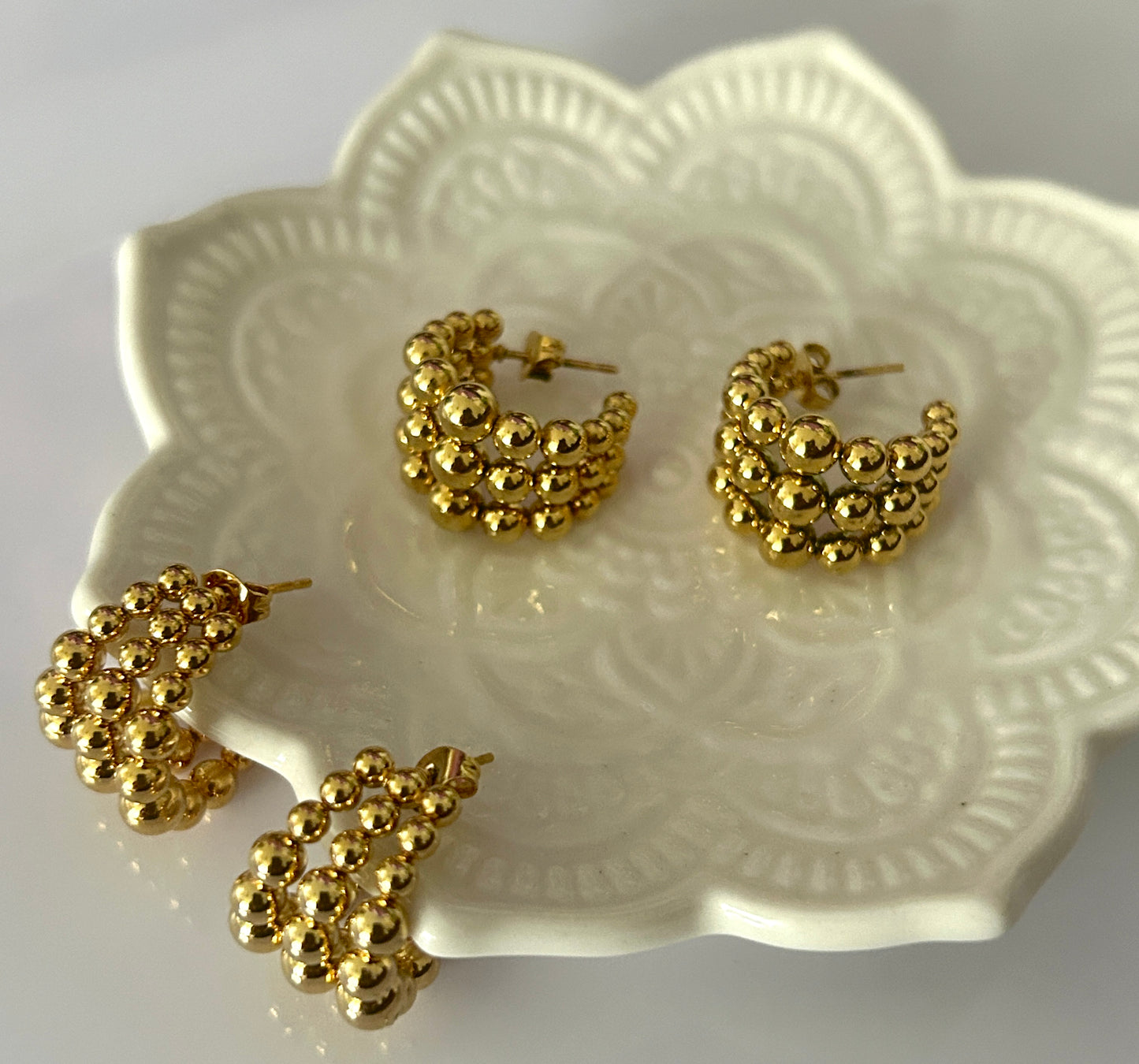 Gold hoop earrings on a decorative white plate
