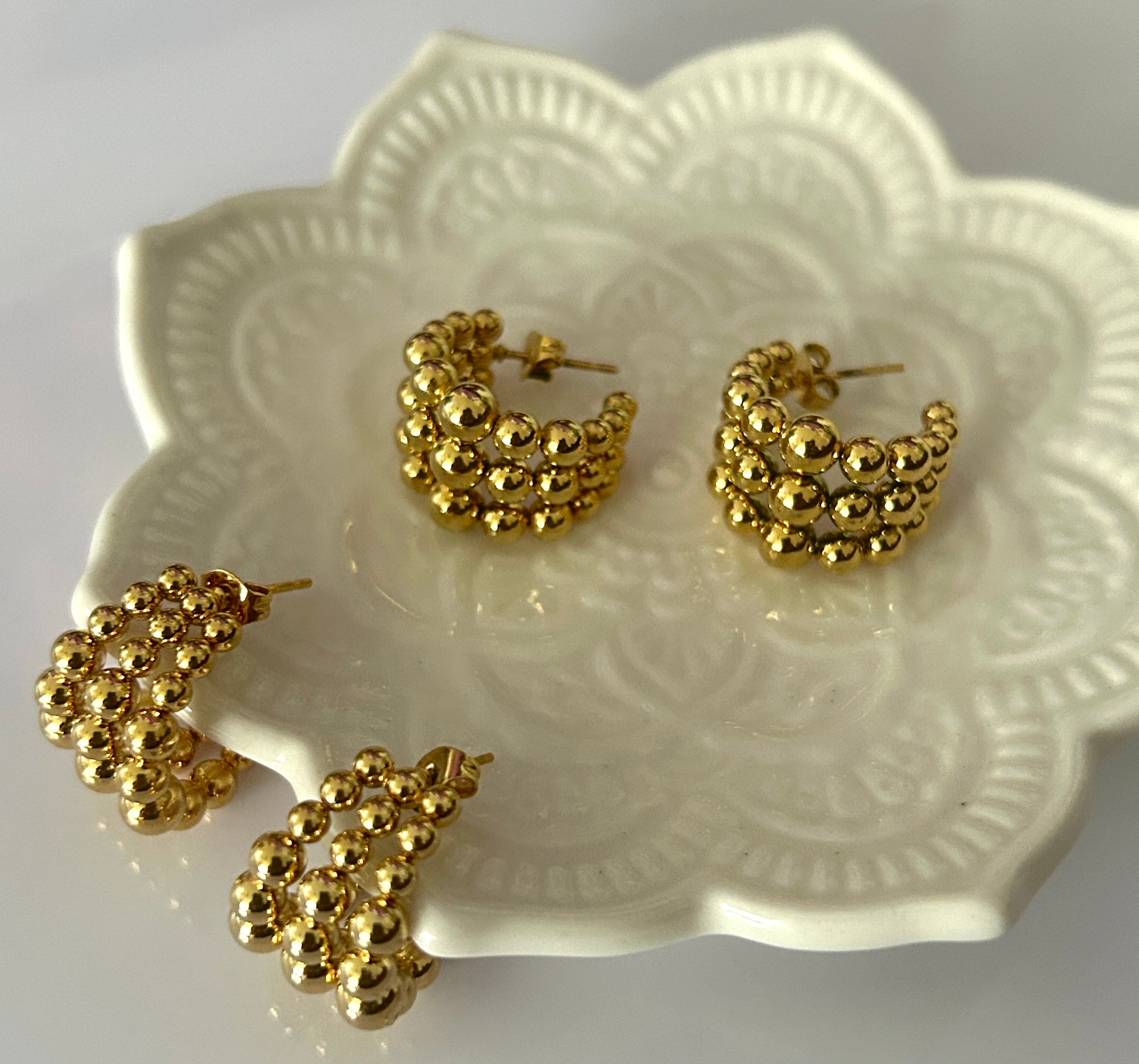 Gold hoop earrings on a decorative white plate