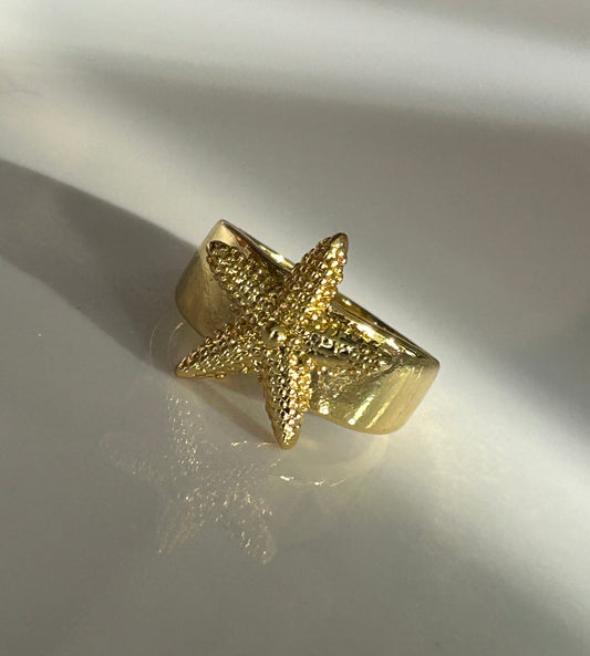 Gold starfish ring on a reflective surface