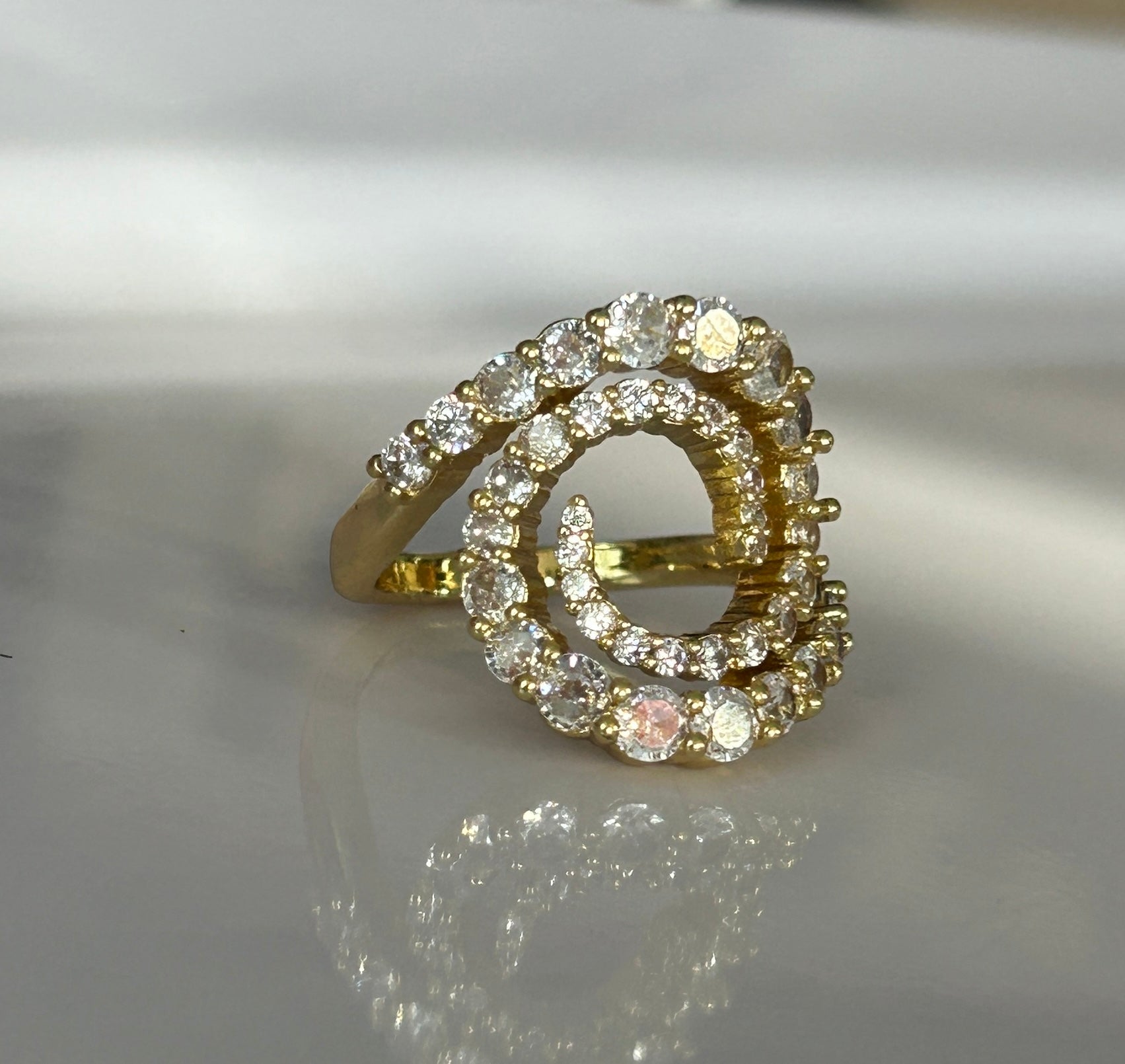 Gold ring with diamond accents on a reflective surface