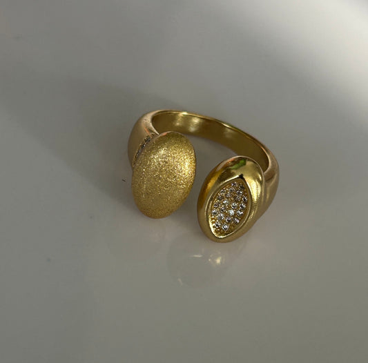 Gold ring with textured design on a light gray background