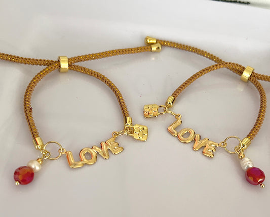 Two gold bracelets with 'LOVE' charms on a light background